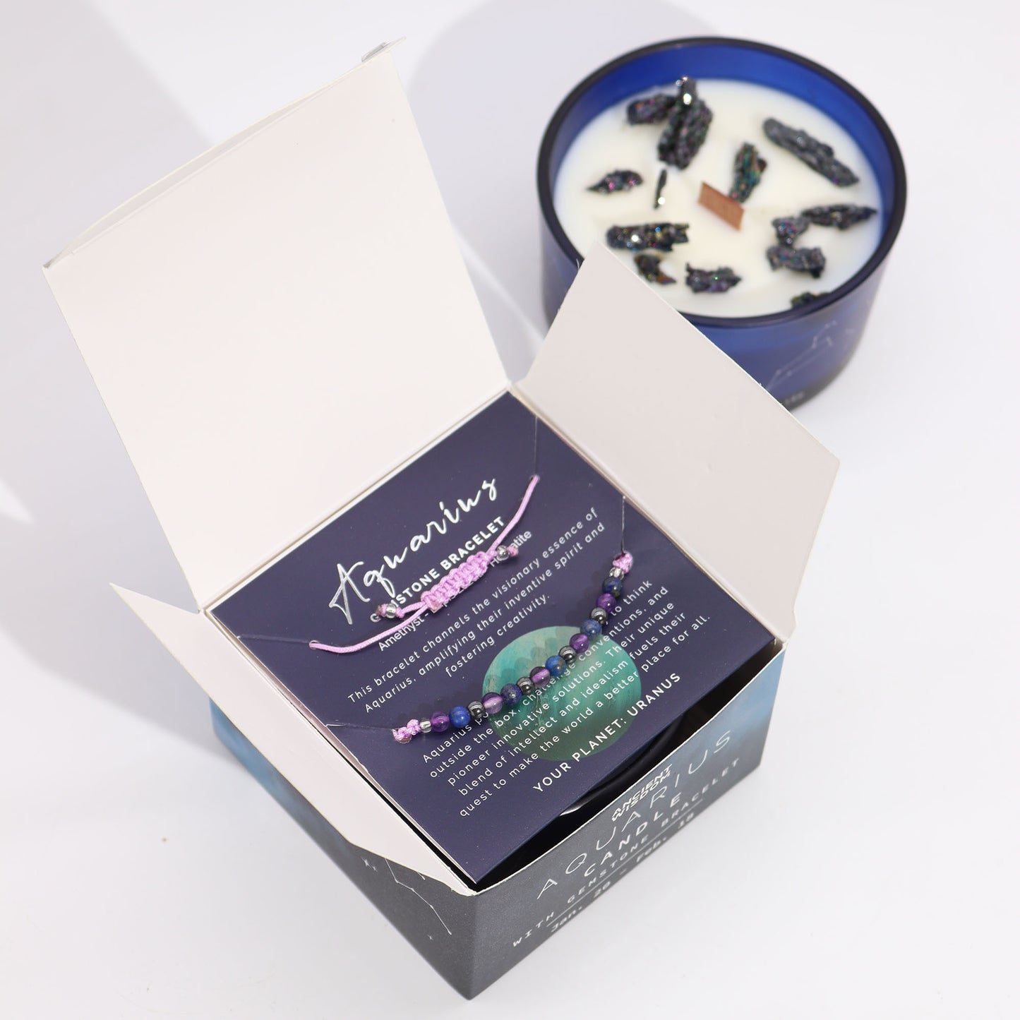 Aquarius astrology candle with crystals by Samsara Wellbeing in blue glass jar with informational card and bracelet