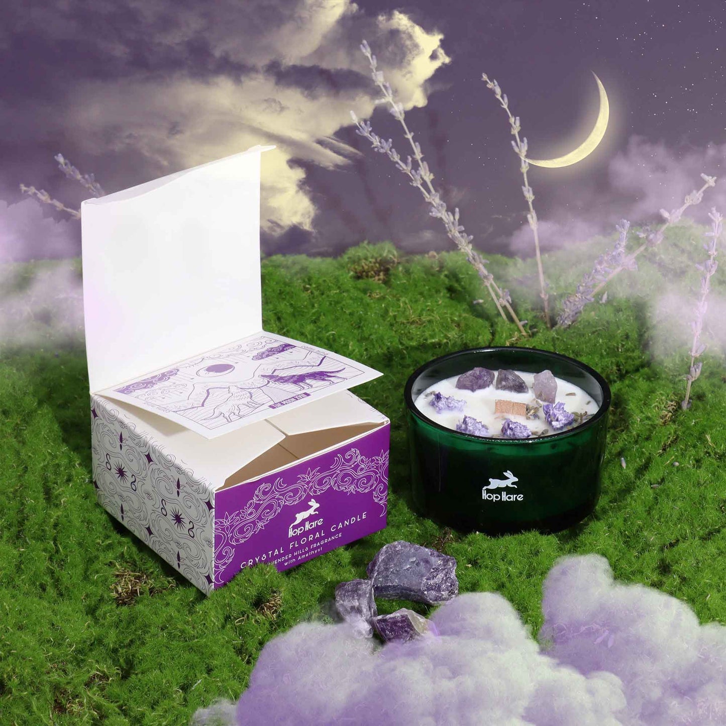 Crystal infused flower candle in black jar with purple crystals next to open decorative box on green moss