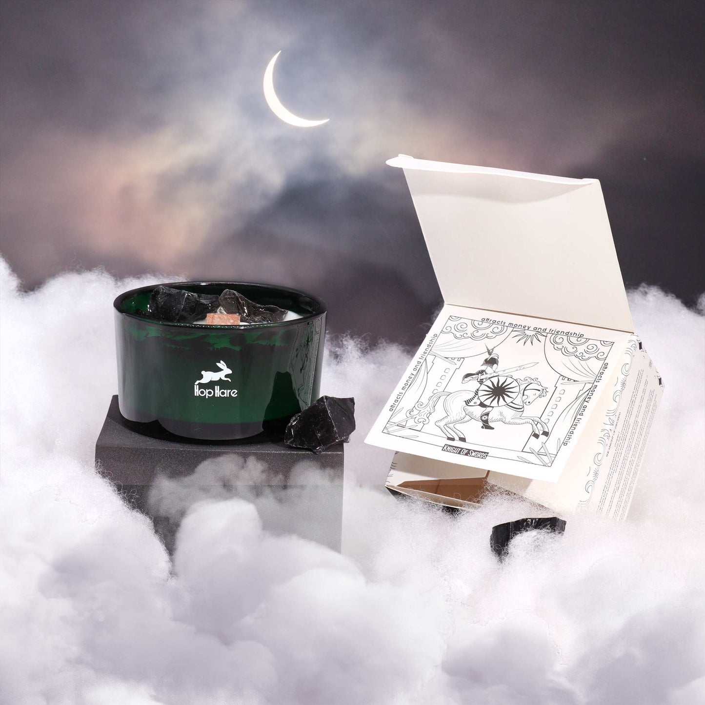Crystal infused flower candle in green glass jar with black crystals and decorative packaging under crescent moon