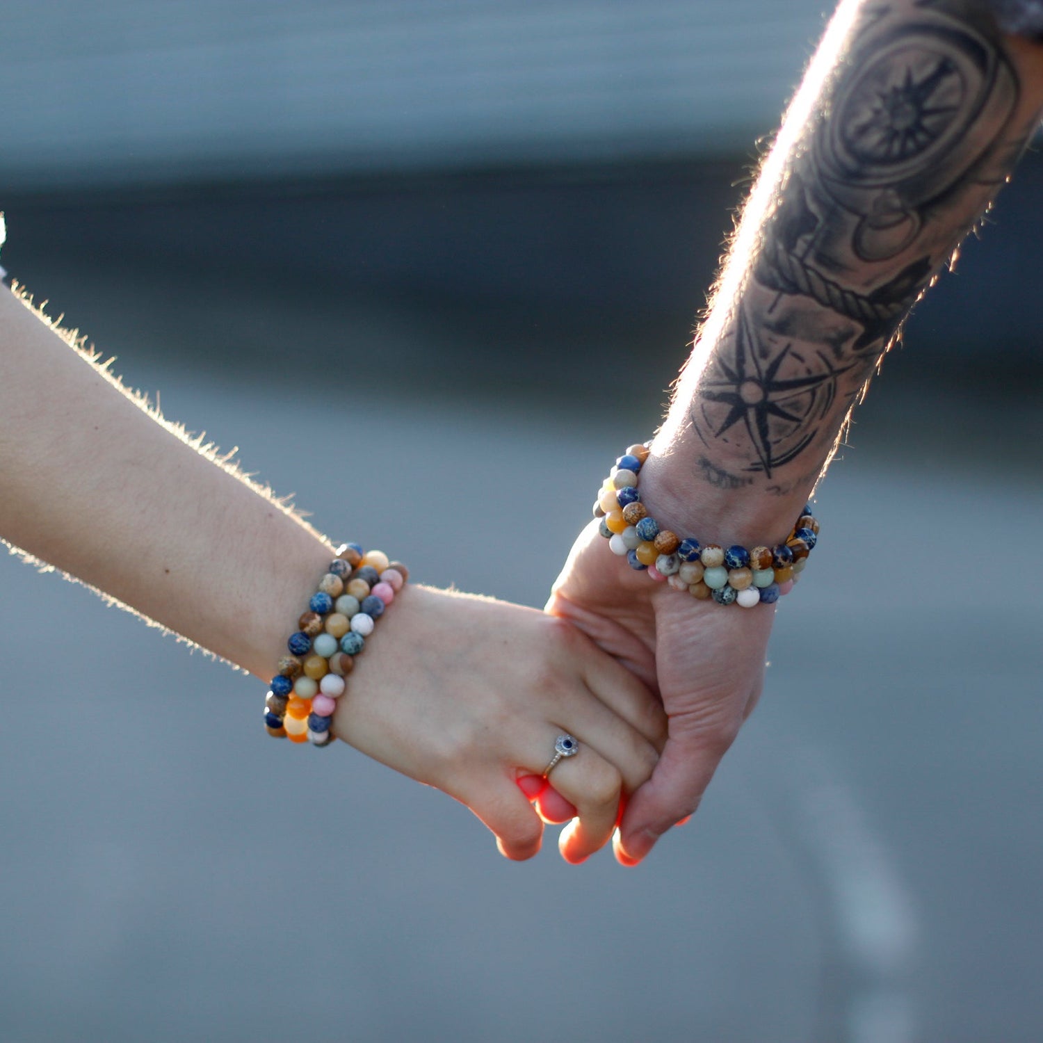 Close up of two people holding hands wearing colourful gemstone friendship bracelets symbolising their bond