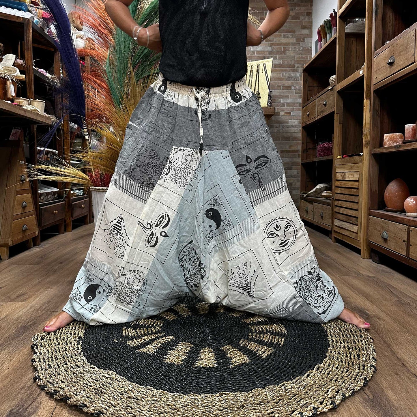 Aladdin Himalayan yoga pants in grey and white with spiritual motifs worn in a wooden room by Samsara Wellbeing