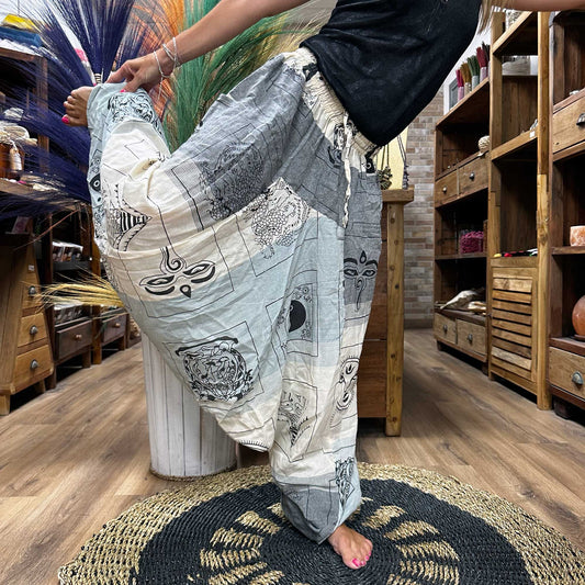 Aladdin Himalayan yoga pants by Samsara Wellbeing in grey and white with spiritual prints worn during a yoga pose indoors