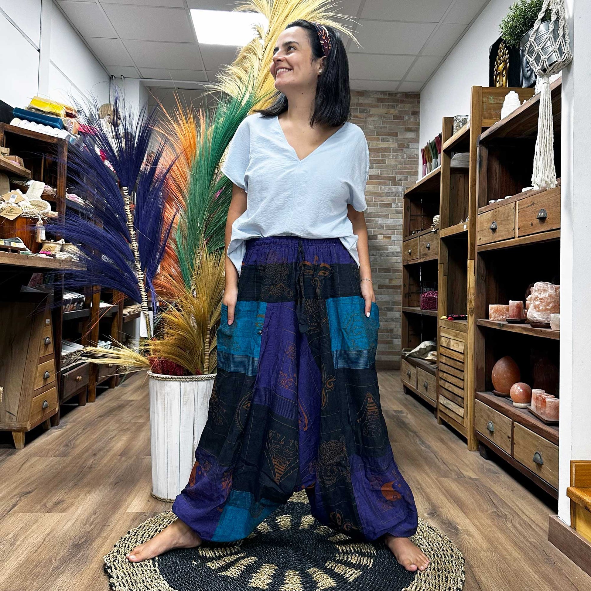Woman wearing Samsara Wellbeing Aladdin style yoga pants in blue and black patchwork design indoors
