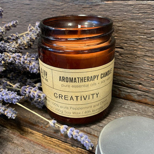 Creativity aromatherapy soy wax essential oil candle in amber glass jar with lavender on wooden surface