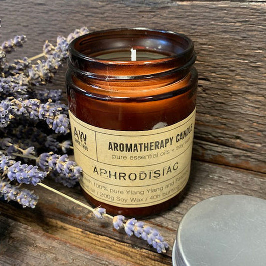 Aromatherapy peace candle in brown glass jar with lavender flowers and silver lid on wooden surface