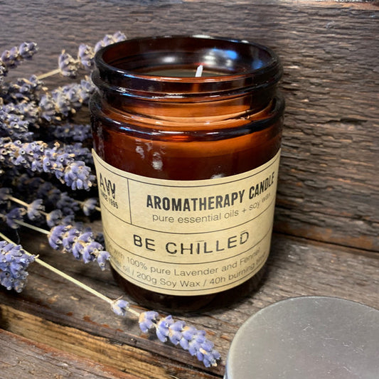 Relaxing soy wax candle in brown jar with lavender scent and dried lavender flowers beside it