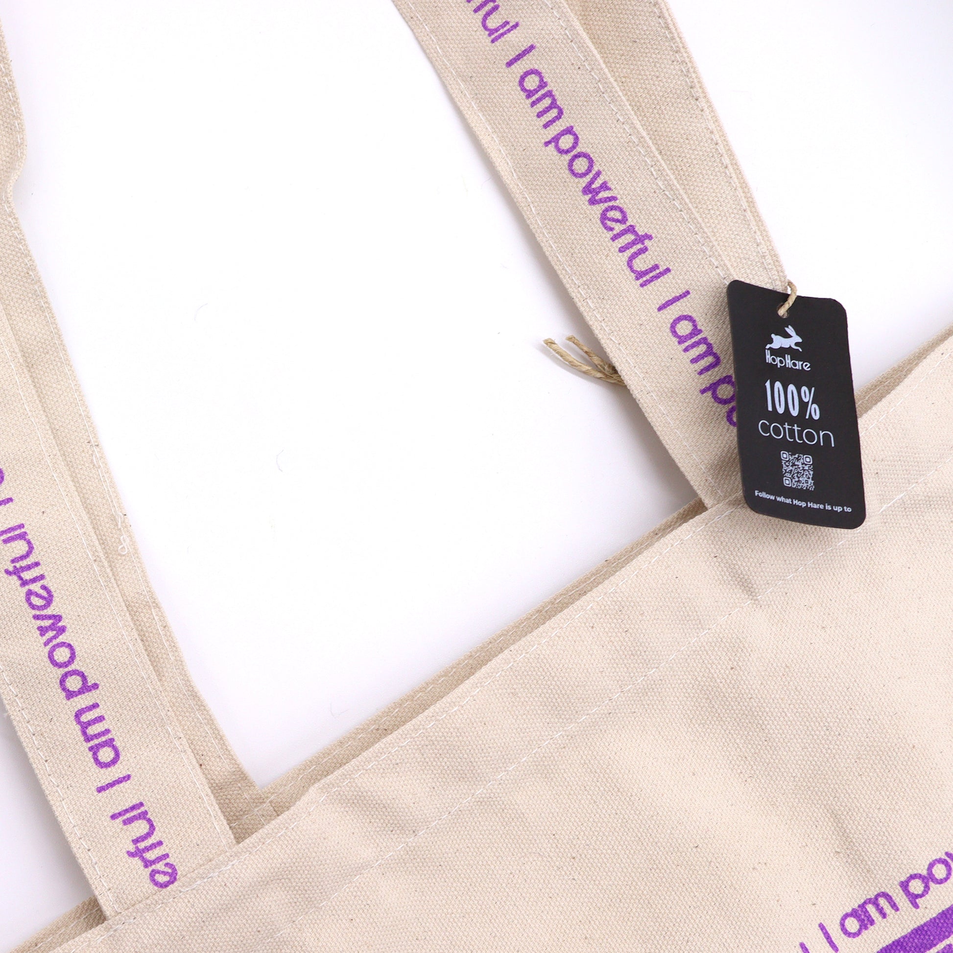 Eco friendly motivational tote bag with 100 percent cotton fabric and purple empowering text on handles