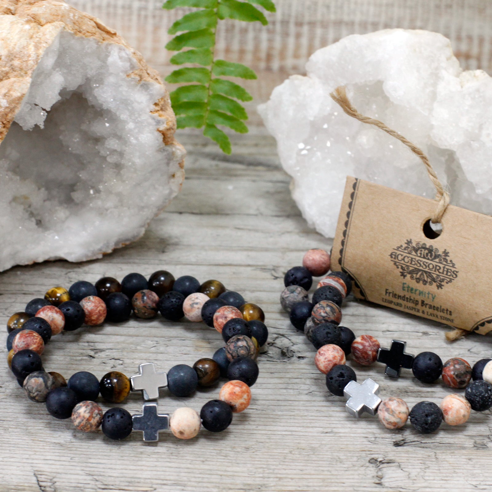 Gemstone friendship bracelets with black cross beads displayed on wooden surface with crystal geodes