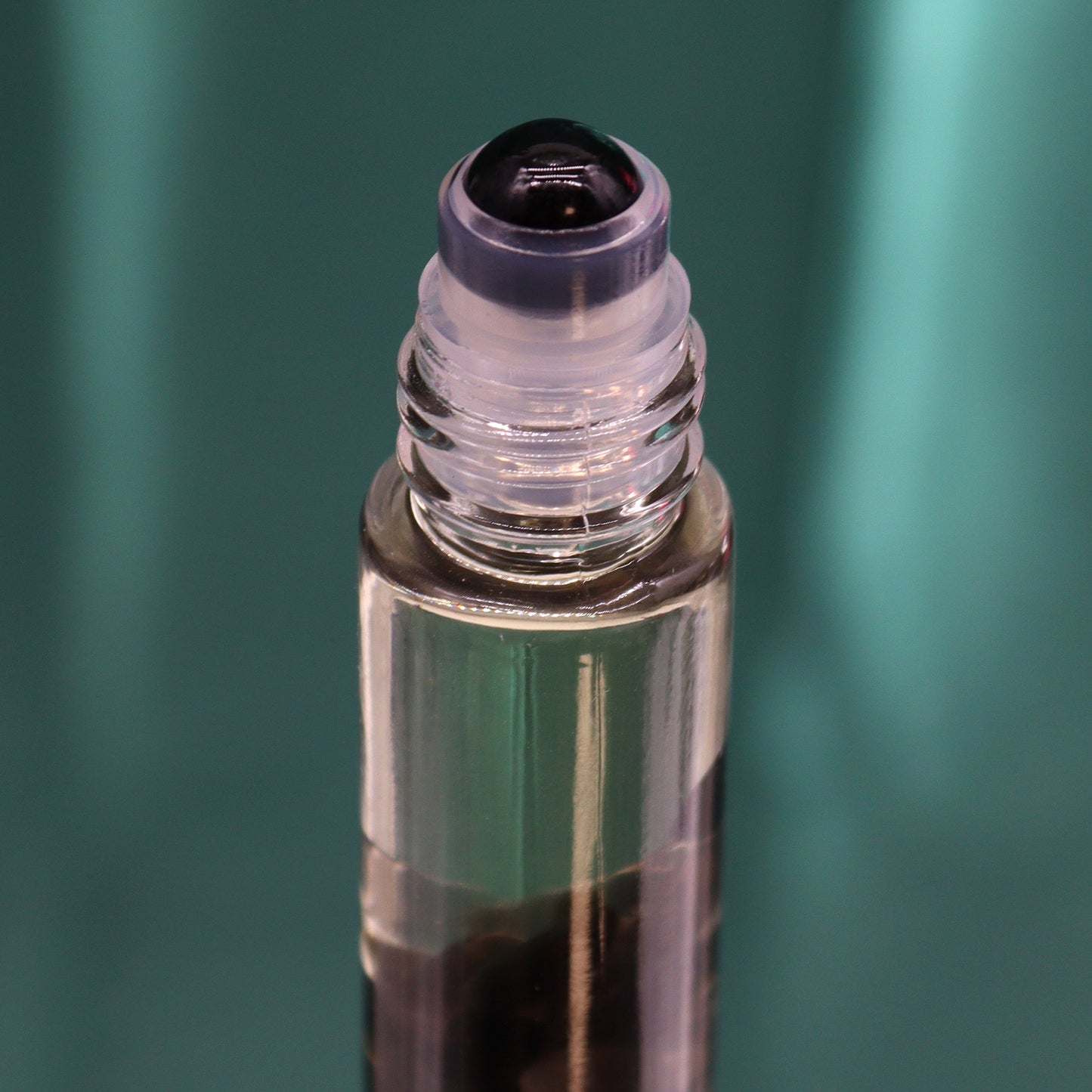 Close-up of a clear glass bottle with a black rollerball applicator for tarot essential oil roll on