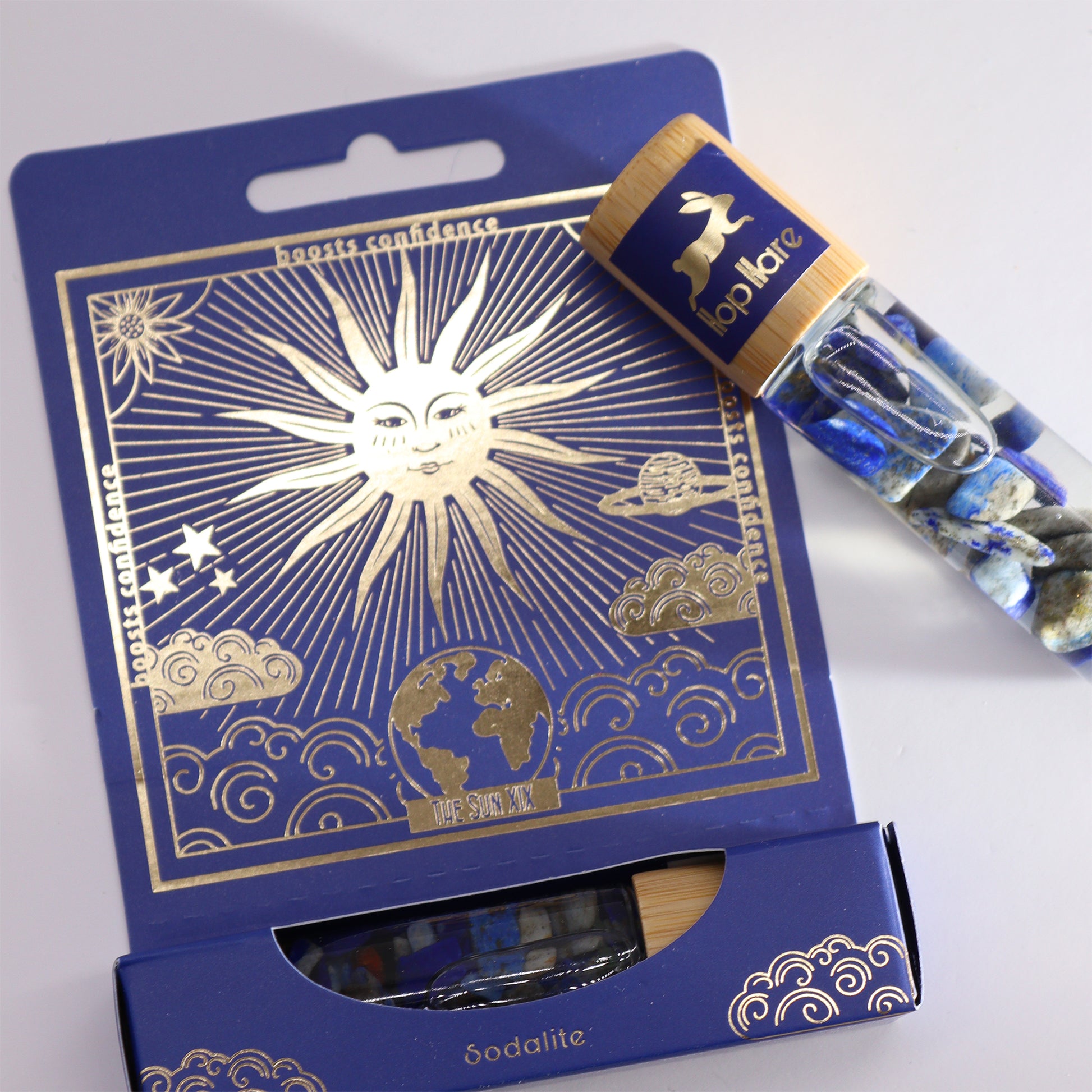 Crystal infused essential oil with sodalite crystals in glass roller bottle and blue celestial themed packaging