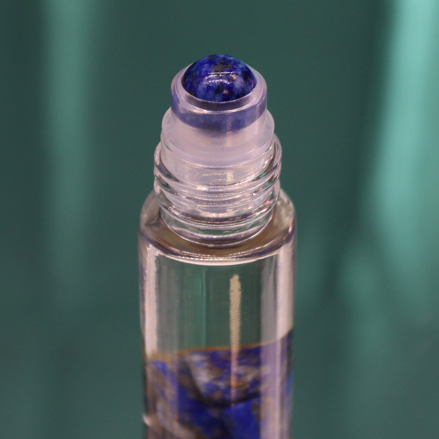 Close-up of a crystal infused essential oil roller bottle with a blue crystal rollerball