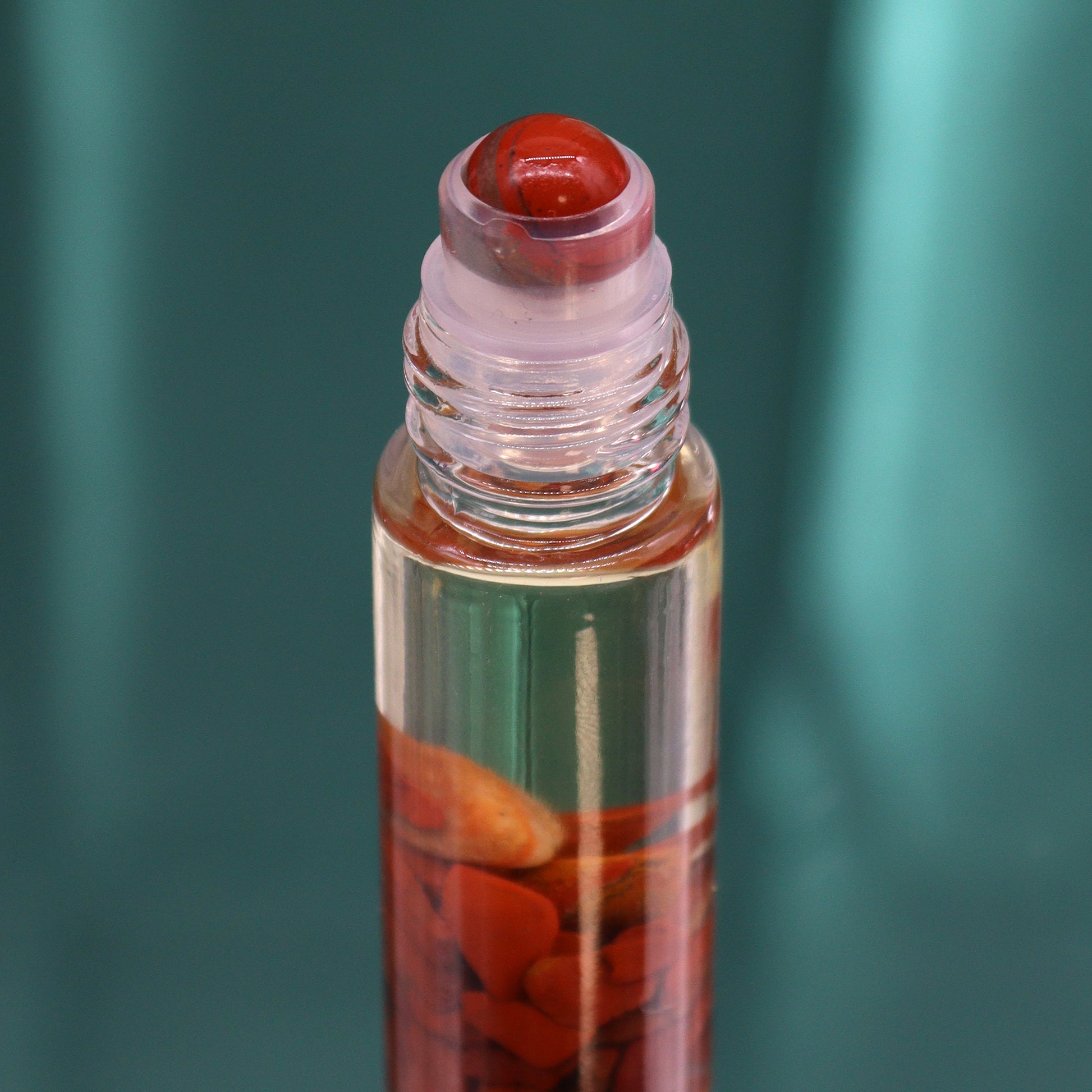 Close-up of tarot essential oil roller with red stone rollerball and clear glass bottle