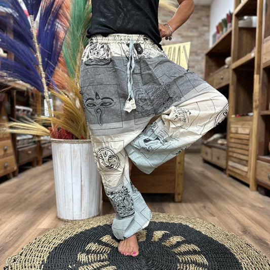 Samsara Wellbeing Himalayan yoga pants featuring grey and cream patchwork with spiritual motifs worn indoors
