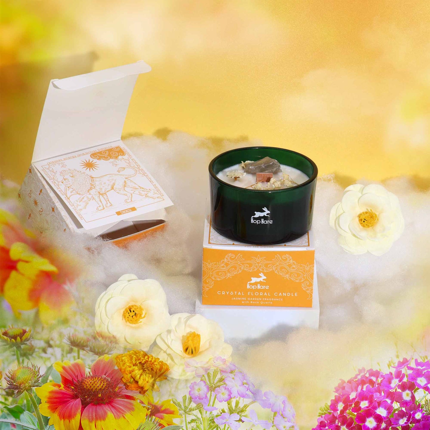 Aromatherapy candle with crystals in a green glass jar on decorative packaging surrounded by flowers