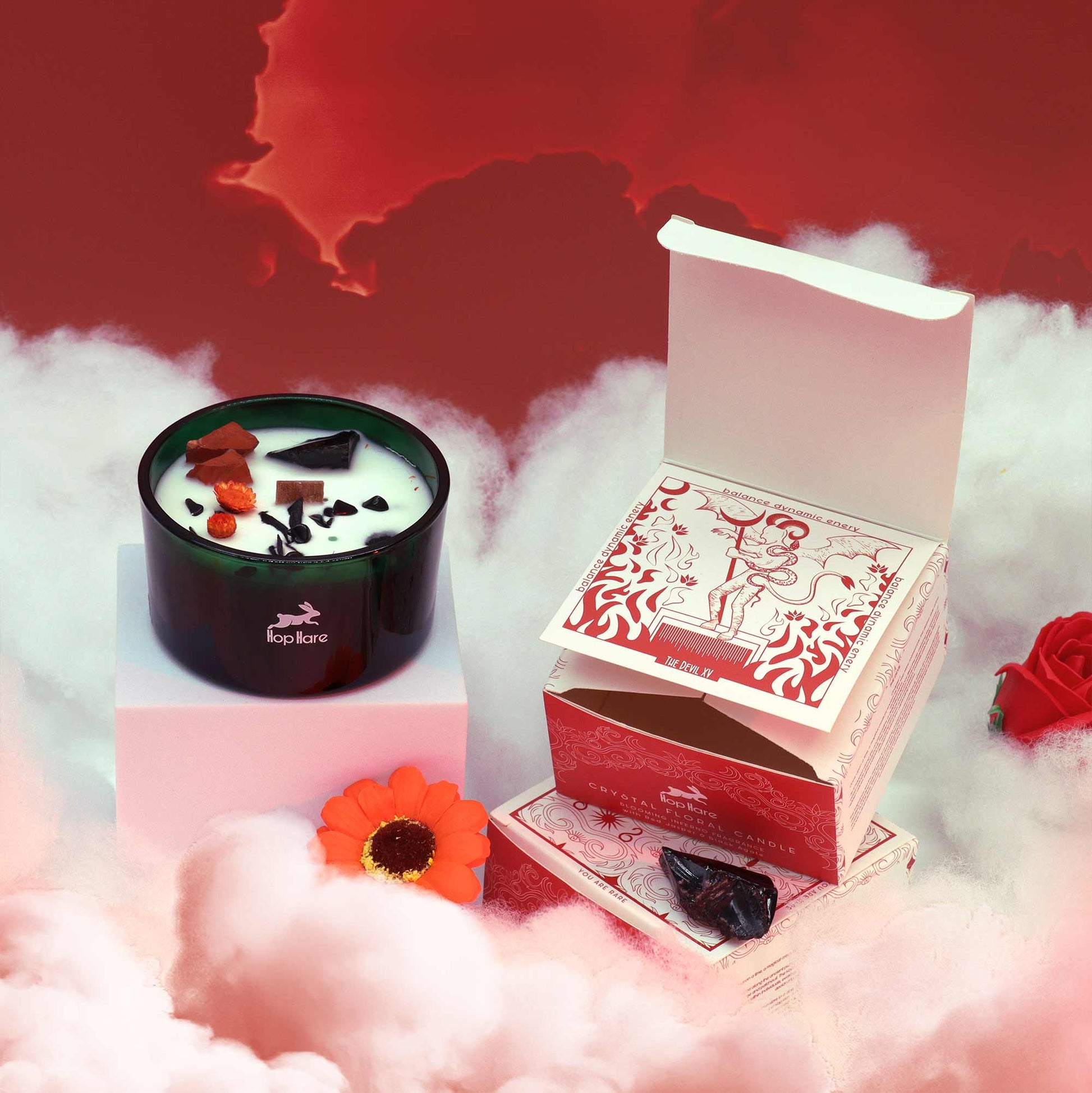 Crystal infused candle in black glass jar with crystals on wax and decorative red and white packaging