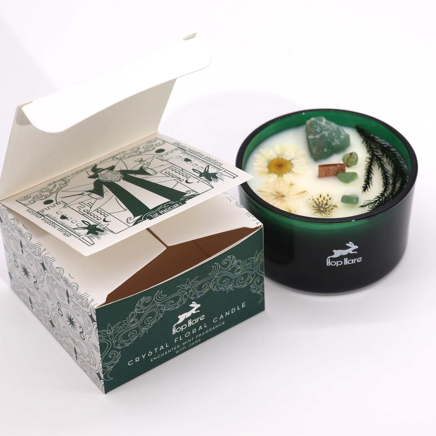 Crystal infused flower candle in green glass container with dried flowers and crystals beside decorative packaging