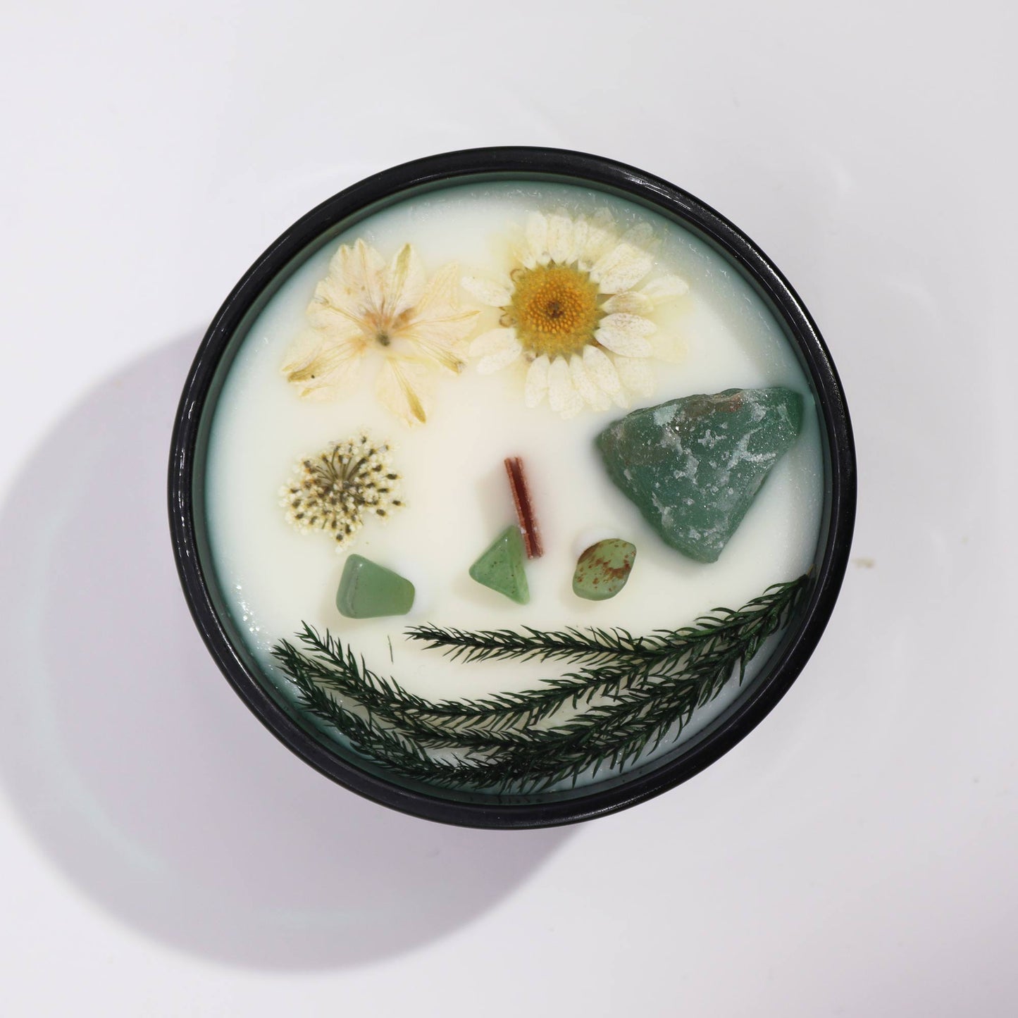 Crystal infused flower candle with dried flowers and green crystals in black container