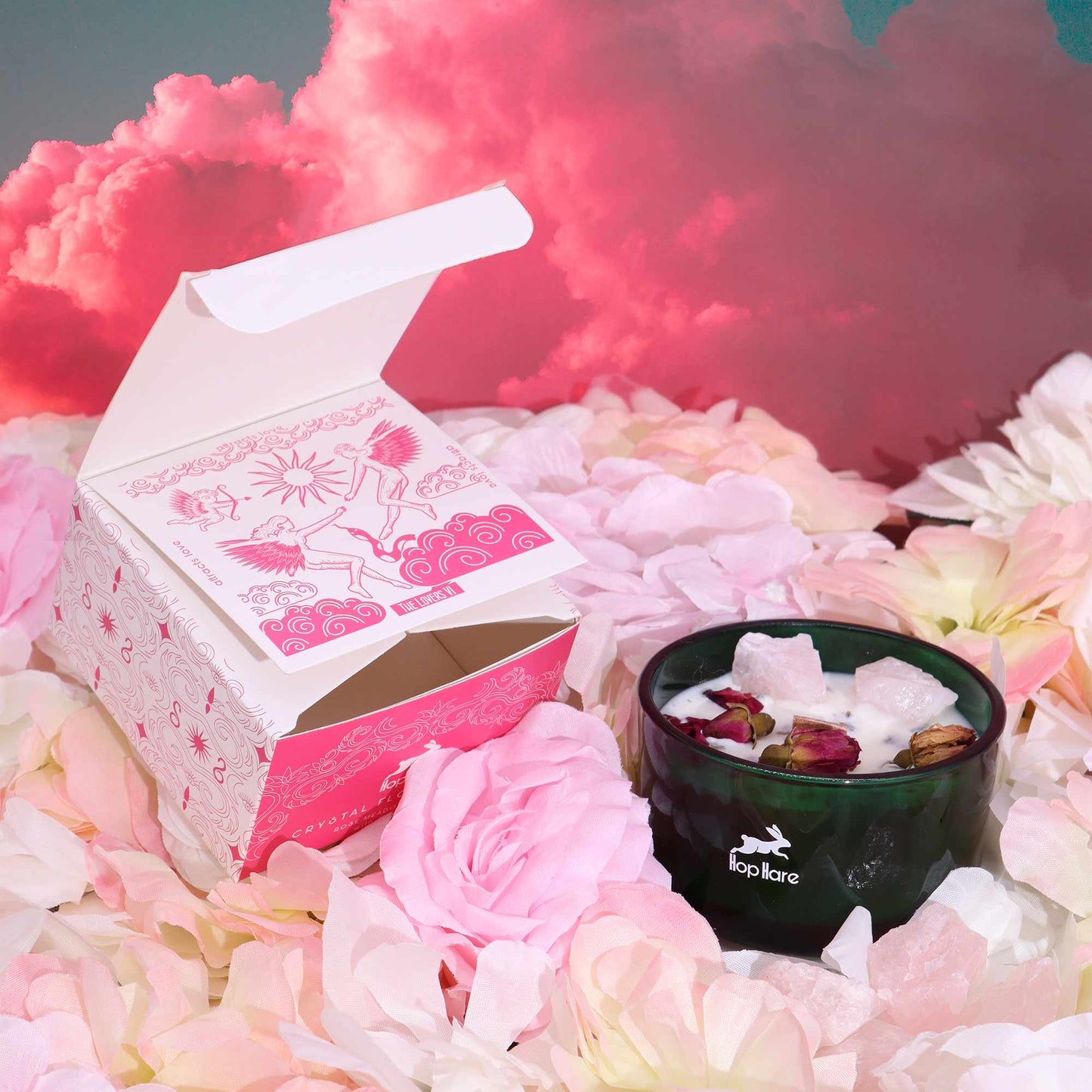 Crystal magic flower candle in black jar with rose petals and crystals surrounded by soft pink flowers