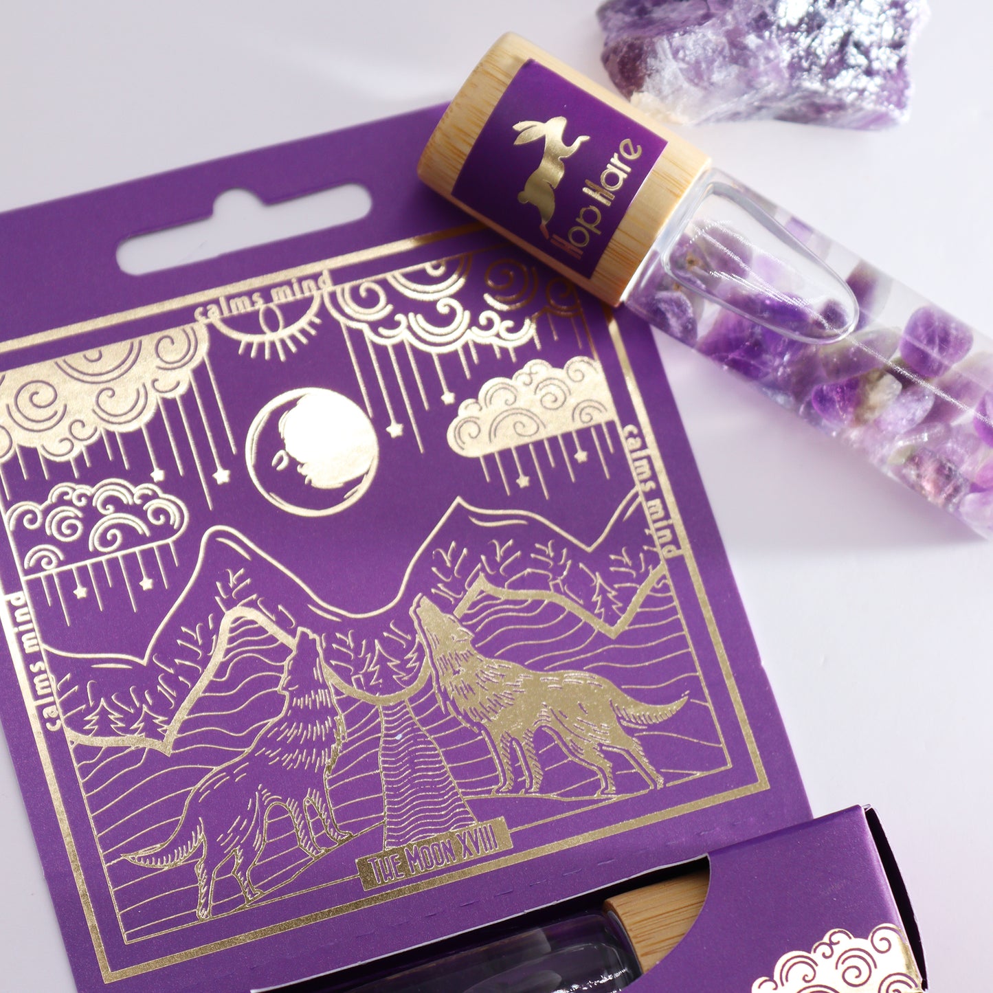 Tarot moon essential oil roll on with amethyst crystals in clear bottle and purple gold wolf moon packaging