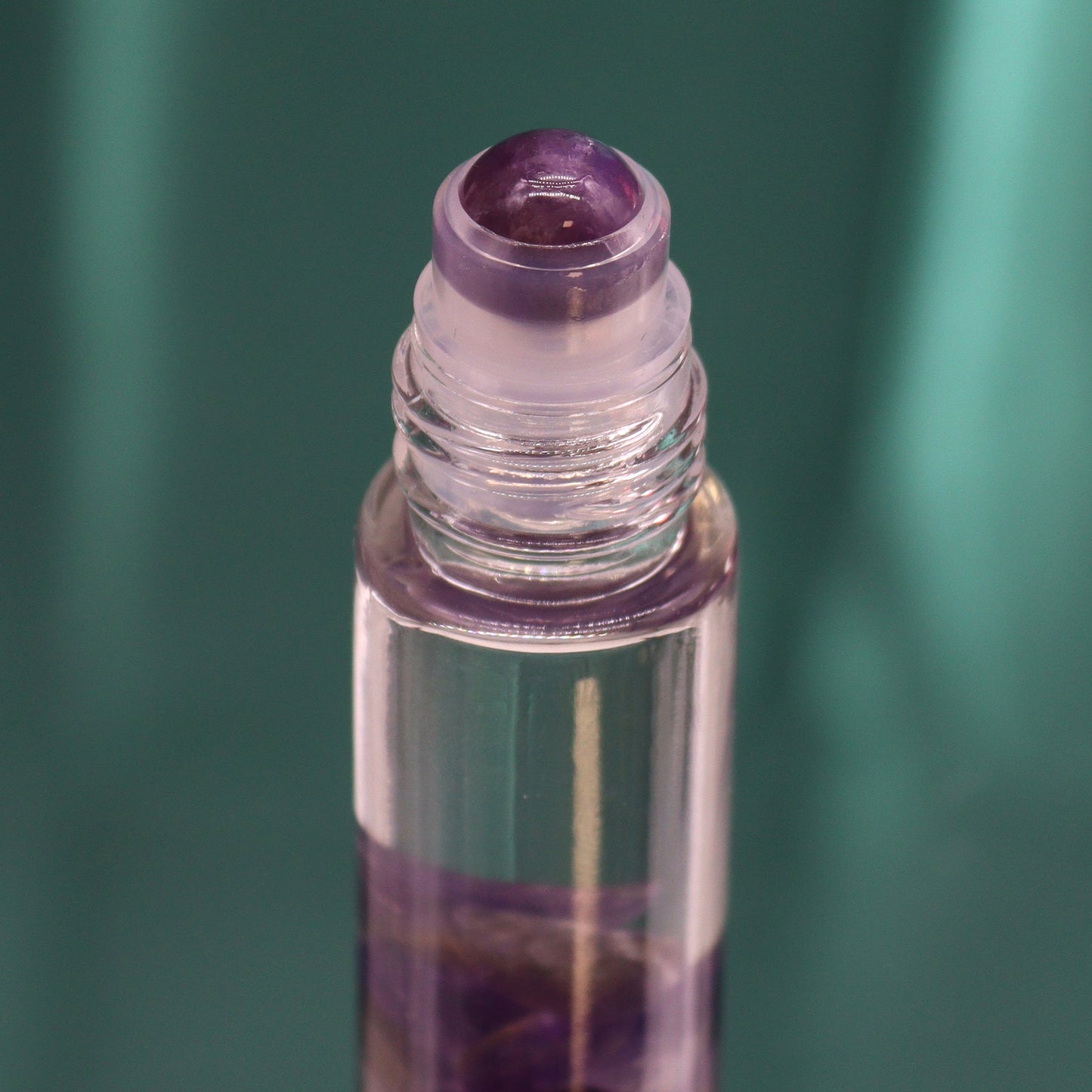 Close-up of tarot moon essential oil roll on bottle with crystal applicator and purple liquid inside