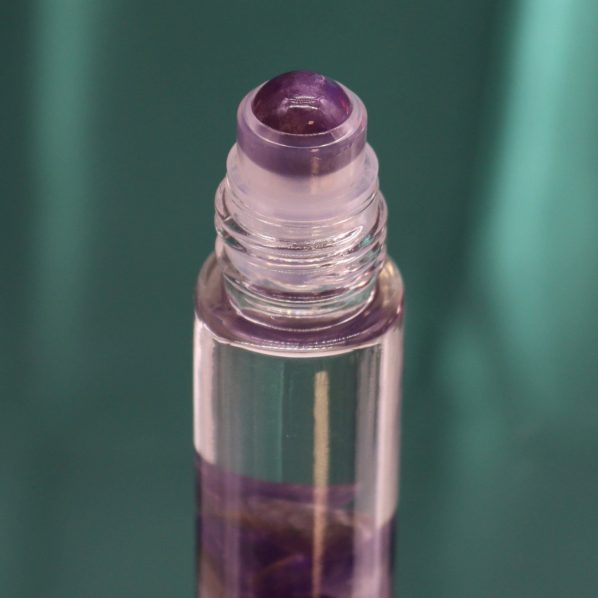 Close-up of tarot moon essential oil roll on bottle with crystal applicator and purple liquid inside