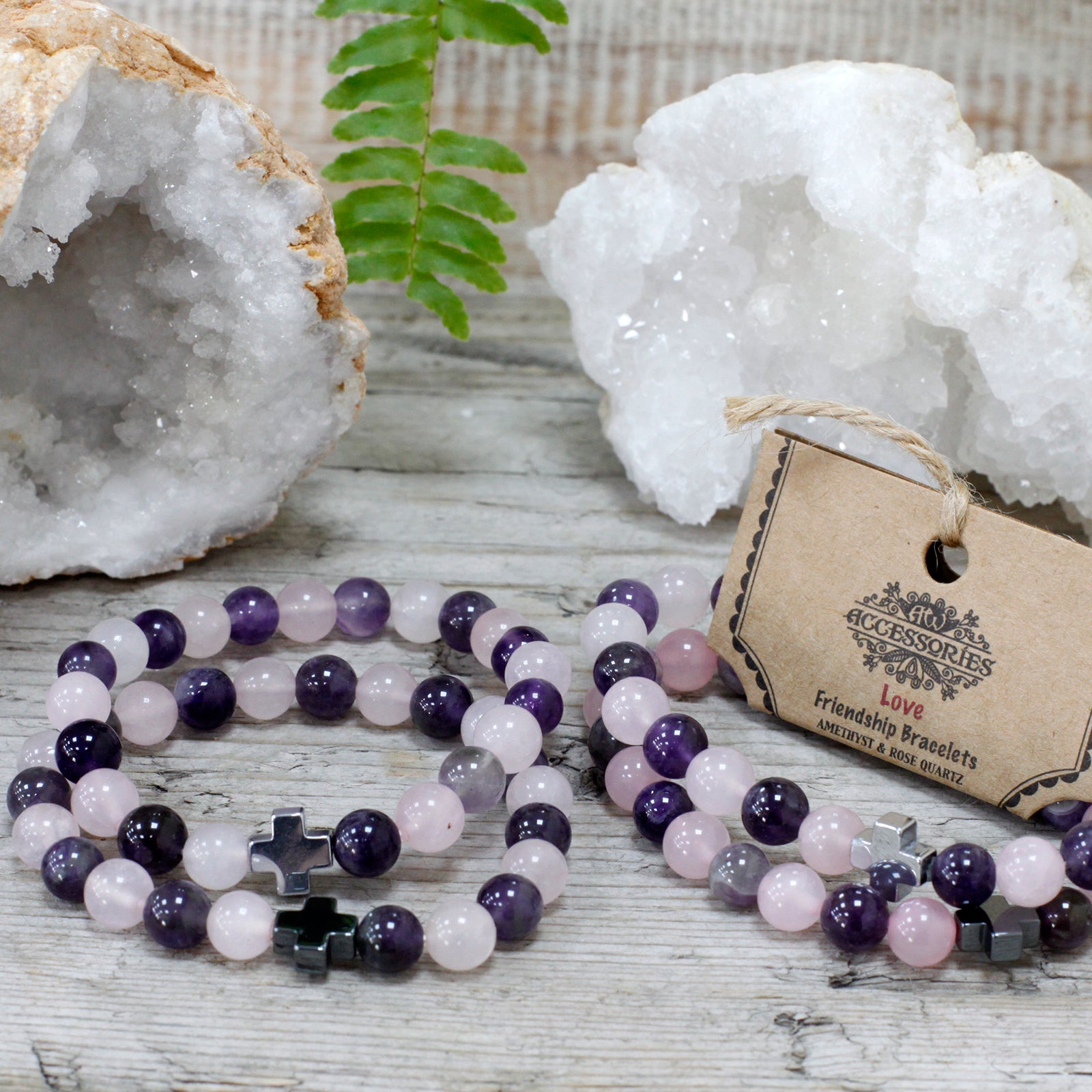 Set of gemstone bracelets for friends with purple and pink beads and cross charms on wooden surface