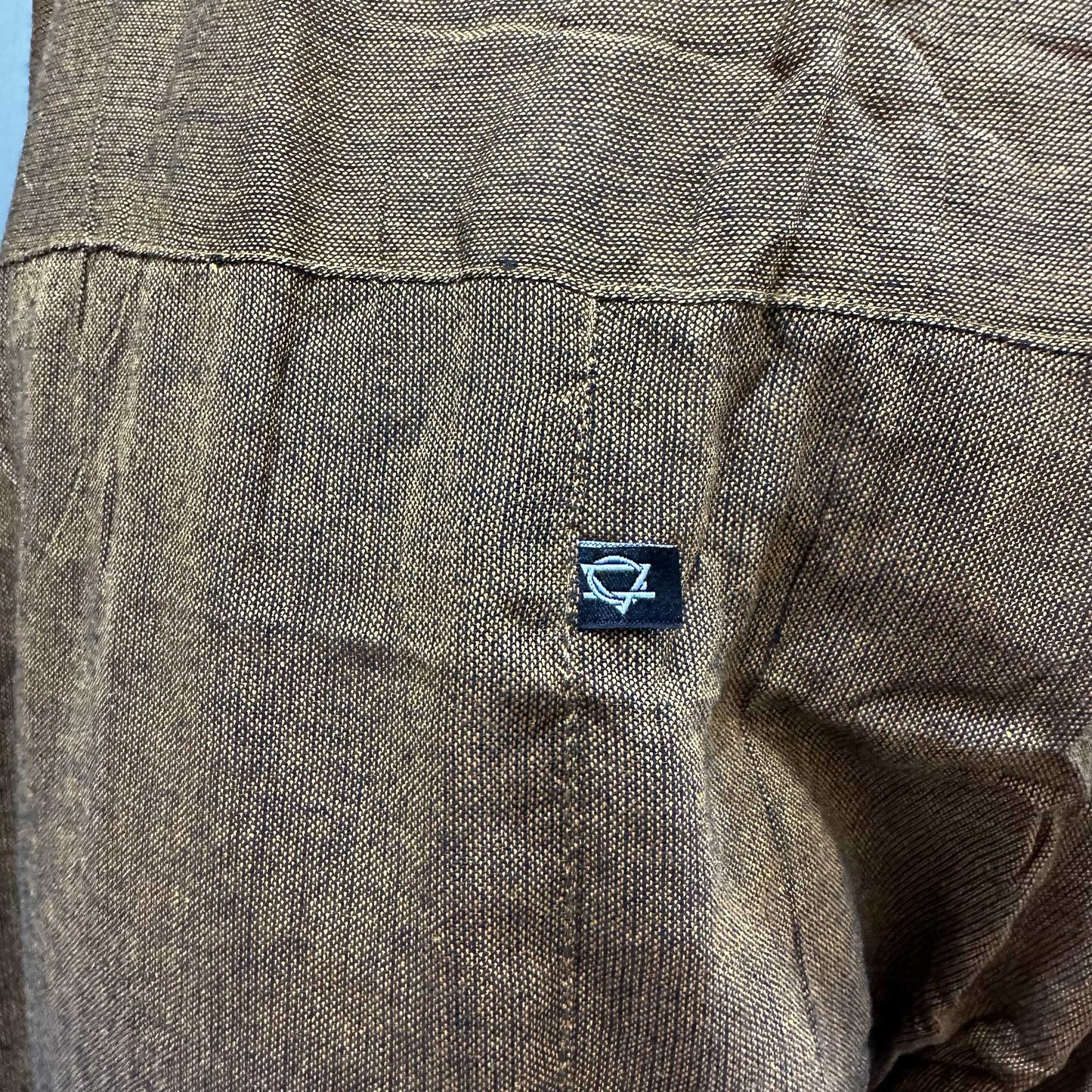 Close-up of brown fabric texture and Samsara Wellbeing logo on Thai fisherman pants for yoga