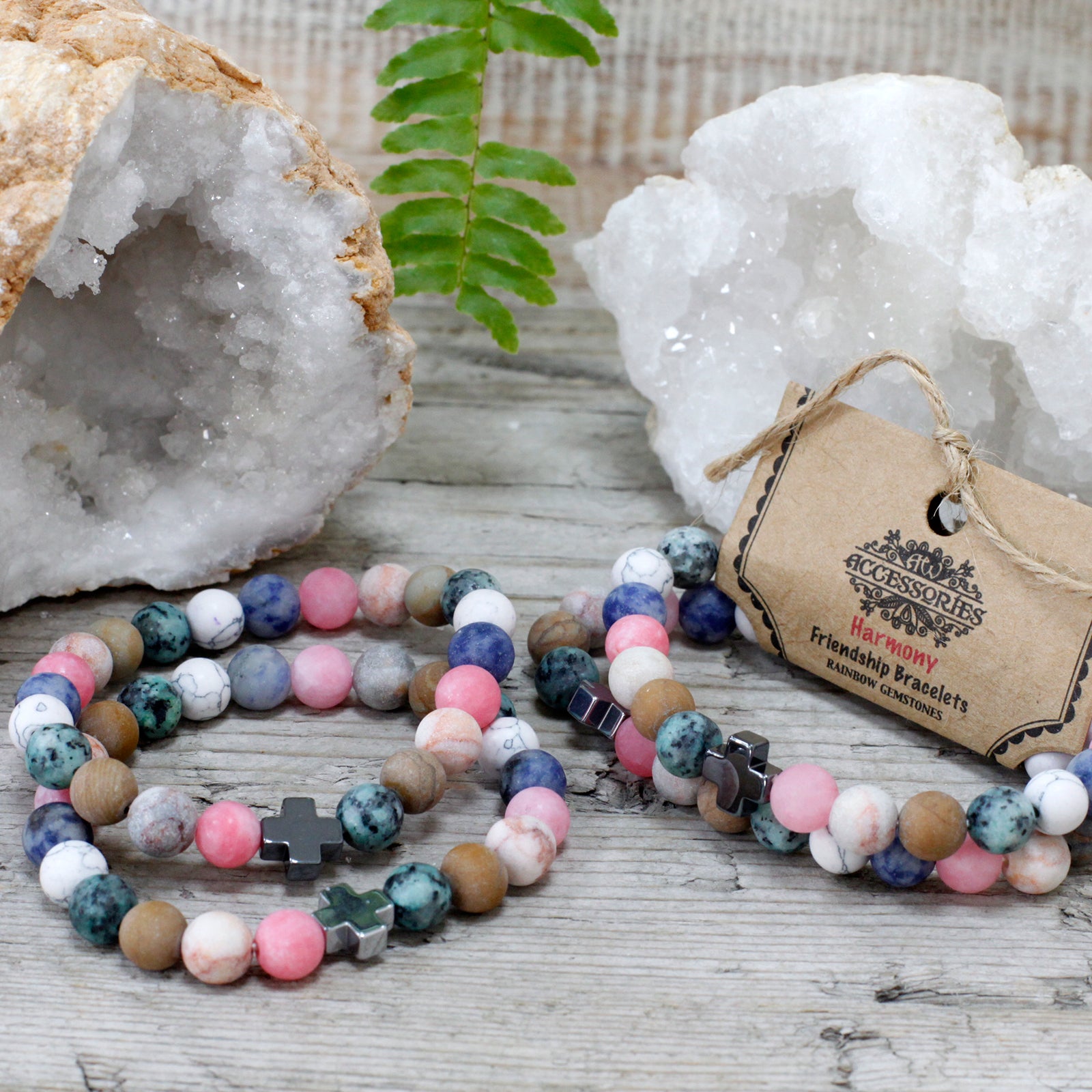 Colourful gemstone friendship bracelets set with cross charms displayed on wooden surface with crystals
